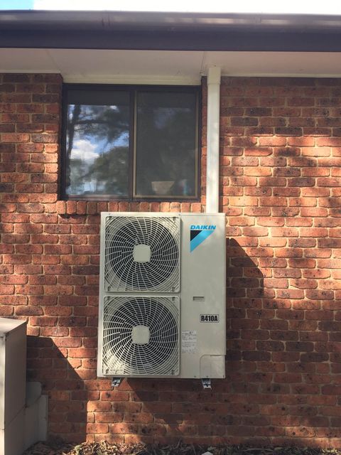 A ducted outdoor unit on wall brackets under a window