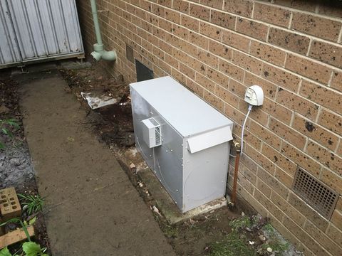 A gas ducted heater with its flue, beside a freshly dug path