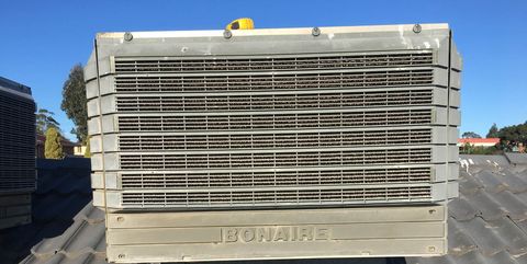 An older evaporative cooler on a tiled roof