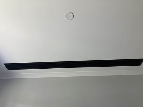 A slot diffuser beside a round ceiling fitting